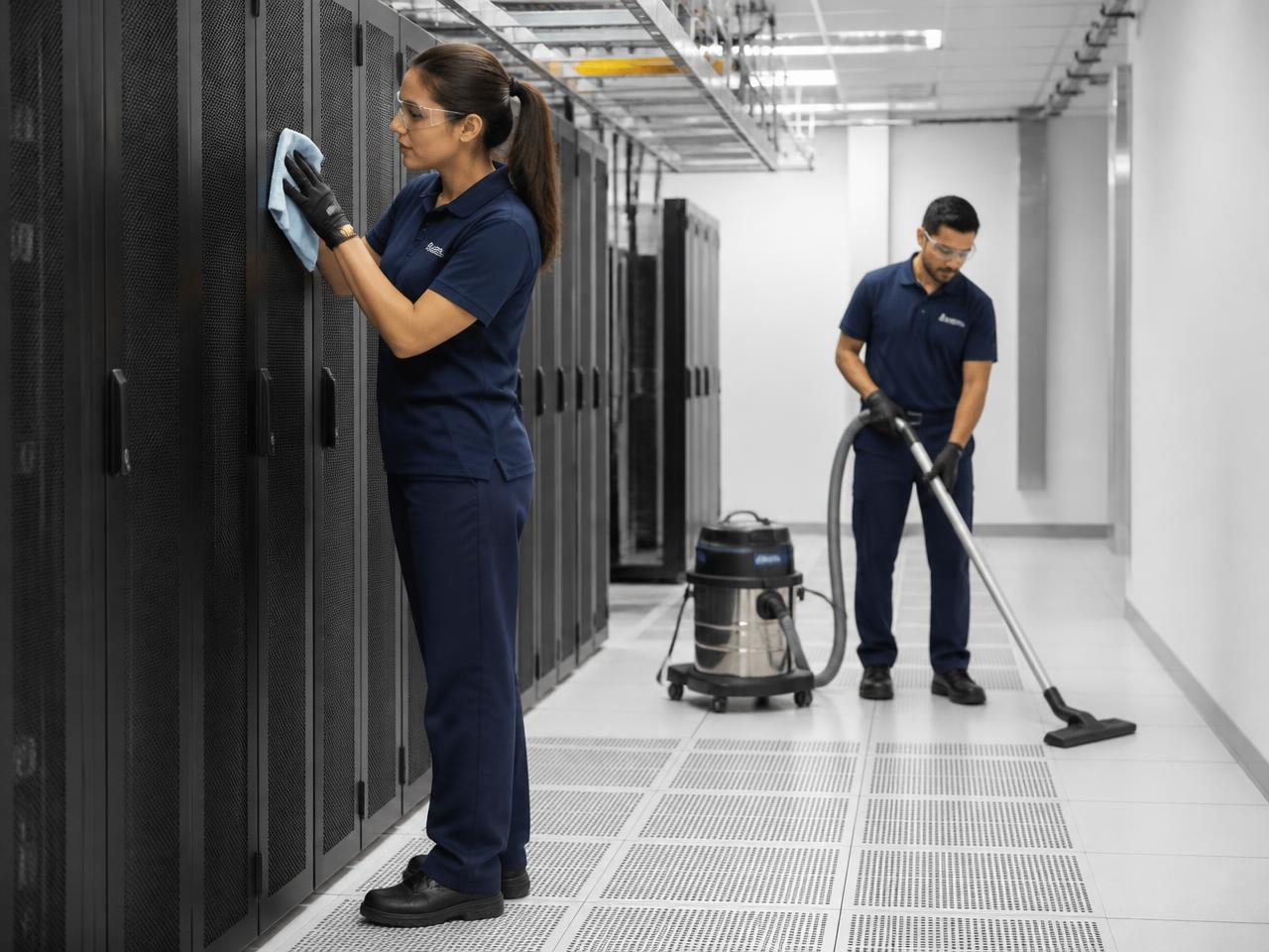 Cleaning crew wiping surfaces and vacuuming fine dust in a nearly completed data center